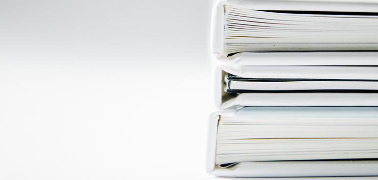 stack of white binders and documents to illustrate food safety management systems