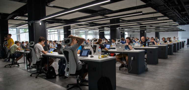 office space with lots of people working on desks with computers