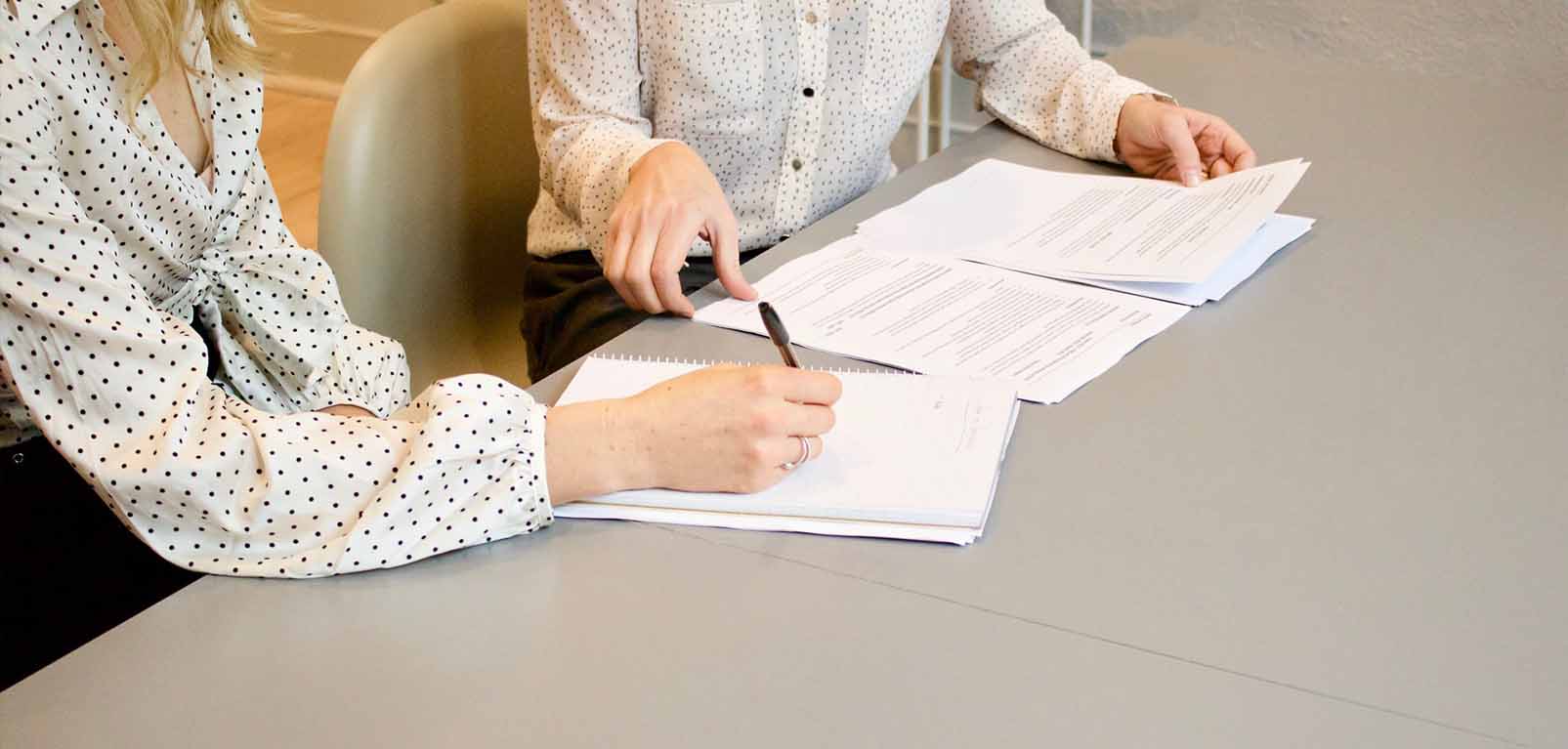 two people sitting going through paper documents on table to illustrate the BRCGS grading system