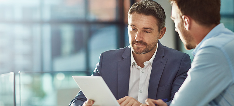 Two men looking at an iPad during a BRC business meeting.