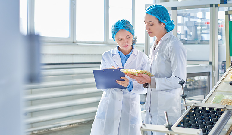 A women holding a clipboard talking to another women about food safety